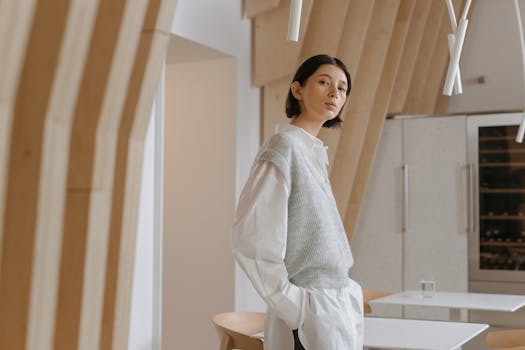 Caucasian woman with short hair stands confidently in a modern, minimalist interior featuring unique architectural design elements.